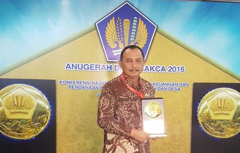 PAMER : Bupati Purworejo Agus Bastian menunjukkan plakat Anugerah Dana Rakca yang diterima dari Menko Perekonomian Darmin Nasution. (BUDI AGUNG/RADAR JOGJA)