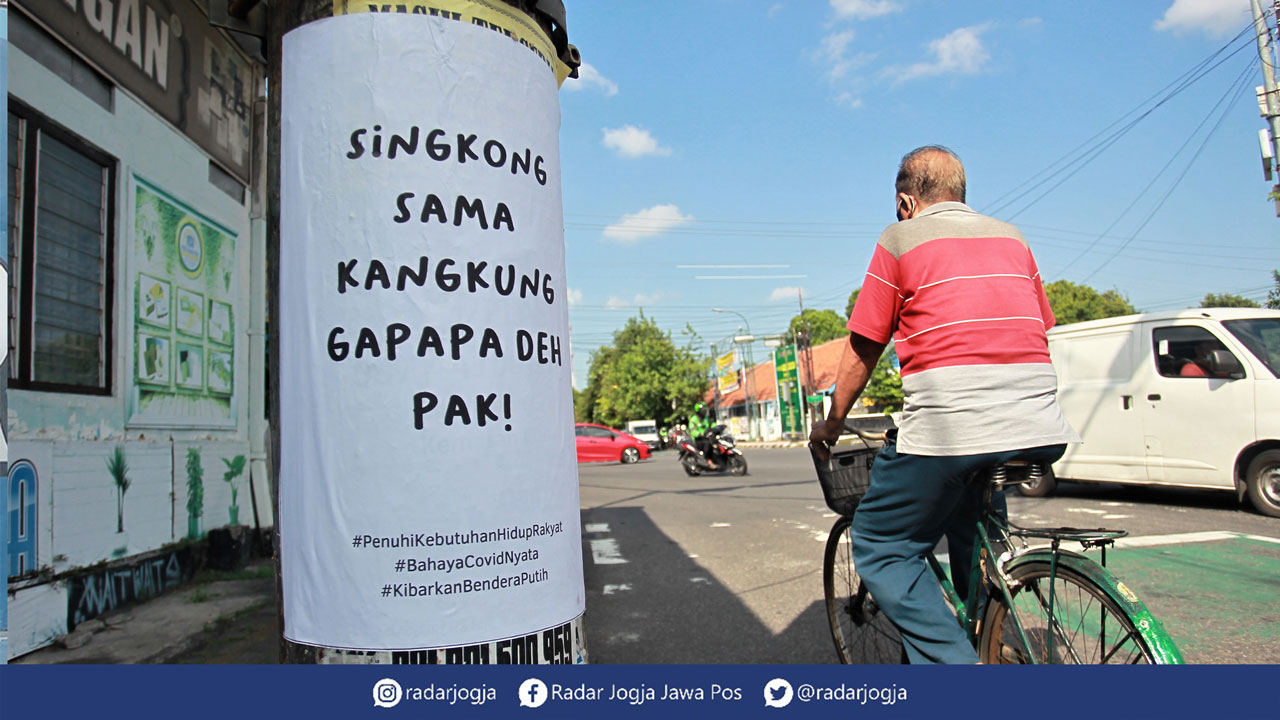 KRITIK: Pengguna jalan melintas di dekat poster bernada satir yang tertempel di kawasan simpang empat Gayam, Jogja, Rabu (21/7). Poster yang diinisiasi oleh Aliansi Mahasiswa Pascasarjana UGM itu menjadi perwakilan suara hati aspirasi sebagian masyarakat
