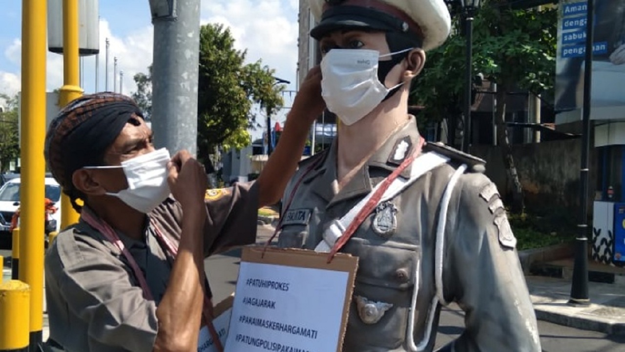 AKSI: Seorang aktivis sosial di Jogjakarta Baharuddin Kamba, melakukan aksi simpatik sekaligus unik.  Aksi berupa ajakan untuk mentaati protokol kesehatan (prokes) ini dilakukannya dengan cara memasangi masker patung polisi yang berada di perempatan Grame