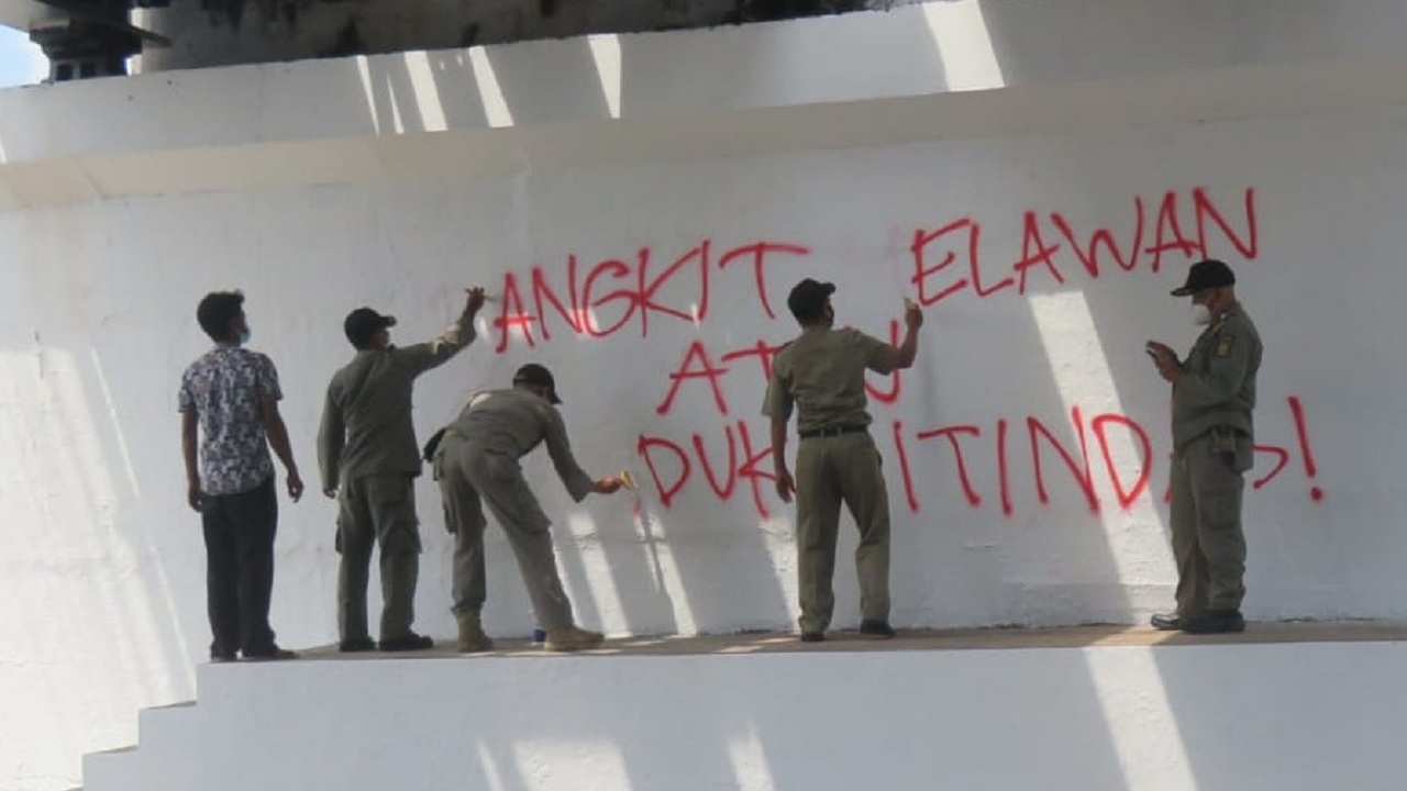 HAPUS: Satpol PP Kota Jogja,menghapus   ,grafiti karya Yogya Street Art Studio Banagkit Melawan atau Tunduk Ditindas yang dibuat di dinding jembatan kewek. (DWI AGUS/RADAR JOGJA)