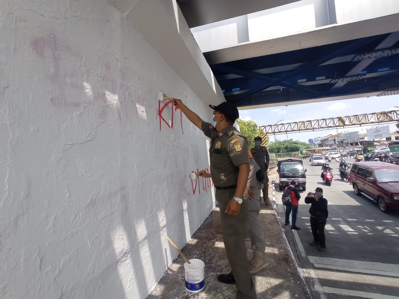 HAPUS:Sat pol PP kota Jogja sedang menghapus tulisan grafiti di bawah jembatan kewek.  (DWI AGUS/RADAR JOGJA)