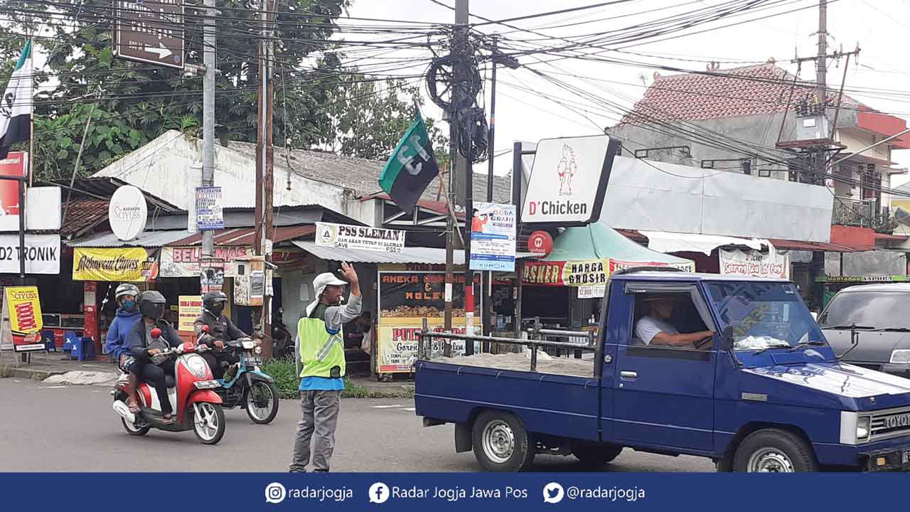 BUTUH RAMBU LALIN: Suasana persimpangan Jalan Purbaya dan Jalan Kebon Agung di  perbatasan Kalurahan Tlogoadi dan Kalurahan Sumberadi, Kapanewon Mlati, Sleman, kemarin (24/11). Tampak seorang pengatur jalan sibuk mengatur lalu lintas kendaraan. (MEITIKA C