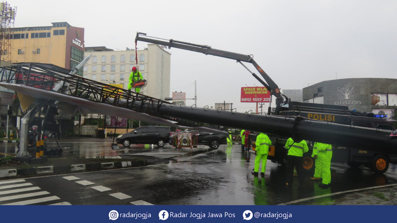 ROBOH : Personel Dit Samapta Polda DIJ mengevakuasi baliho raksasa di simpangempat Ringroad Affandi Condongcatur Depok Sleman yang roboh akibat hujan disertai angin kencang, Rabu sore (12/1). (DWI AGUS/RADAR JOGJA)