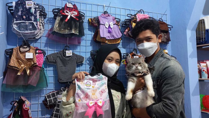BACA PELUANG: Shela, Fitriadi dan kucingnya berswa foto dengan latar belakang baju-baju kucing produksi sendiri. Lokasi di Morty Pet Shop, (4/3).(MEITIKA CANDRA LANTIVA/RADAR JOGJA)