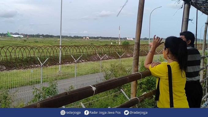 BEDA : Tempat pengamatan pesawat di sisi selatan YIA banyak diakses warga untuk mengisi waktu sambil menunggu saat berbuka bersama,.(HENDRI UTOMO / KULONPROGO)