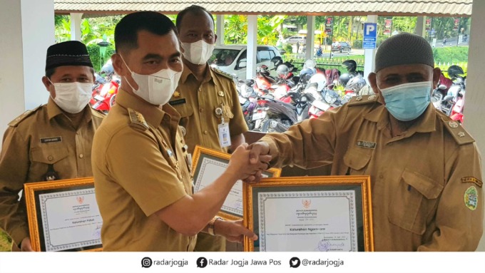 JADI CONTOH - Bupati Gunungkidul, Sunaryanta (kiri) memberikan penghargaan kepada wajib pajak teladan di Kalurahan Patuk (31/5).(GUANWAN/RADAR JOGJA)
