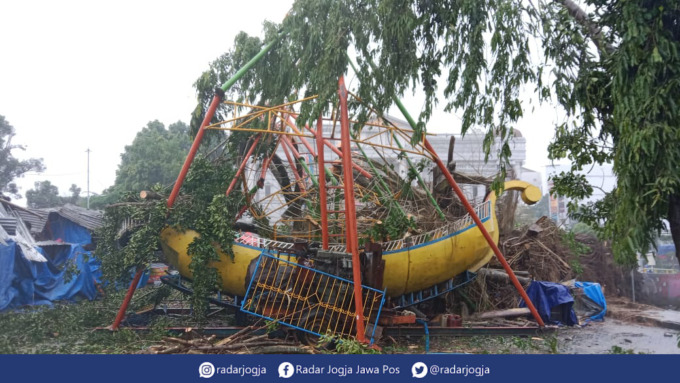 REMUK : Wahana permainan pasar malam di Lapangan Denggung Sleman tertimpa pohon beringin yang roboh akibat hujan deras disertai angin kencang, Senin siang (13/6). (ANNISSA KARIN/RADAR JOGJA)