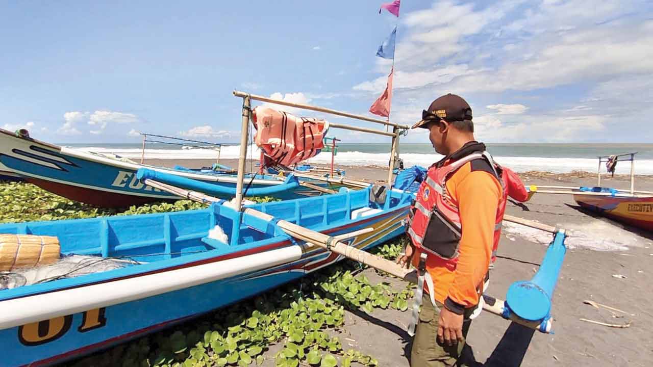 KARAM: Proses penyelamatan nelayan dan perahunya (kanan). Beruntung kedua nelayan Pantai Bugel selamat dan perahu bisa didaratkan ke pantai setempat, kemarin. (HENDRI UTOMO/RADAR JOGJA)