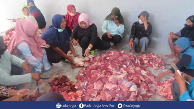 TURUN TANGAN : Bupati Sleman Kustini Sri Purnomo ikut membantu ibu-ibu warga Padukuhan Randusari Cangkringan memotong daging kurban, Minggu (10/7). (DWI AGUS/RADAR JOGJA)