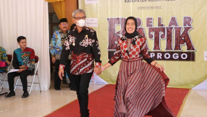 BATIK: Pj Bupati Kulonprogo dan istri memperagakan busana batik dalam GKBK 2022 (kanan), peragawati saat menampilkan batik Kulonprogo di Balai Kalurahan Gulurejo, Kapanewon Lendah, Kulonprogo.(HENDRI UTOMO/RADAR JOGJA)