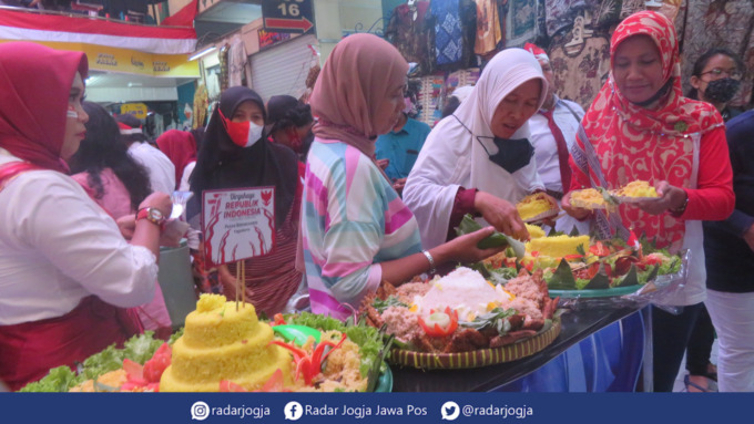 SANTAP : Pengunjung dan pedagang Pasar Beringharjo menikmati sajian nasi tumpeng peringatan Proklamasi Kemerdekaan ke-77 Indonesia di selasar pasar sisi barat, Rabu (17/8). (DWI AGUS/RADAR JOGJA (
