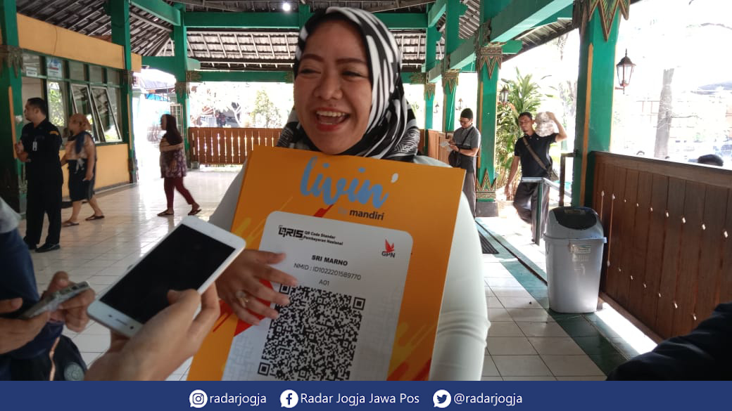 SUMRINGAH : Salah satu pedagang batik di Pasar Beringharjo Fifina Elisa Dewi mengaku sangat terbantu dengan adanya QRIS, Rabu (14/9). (ANNISSA KARIN/RADAR JOGJA)