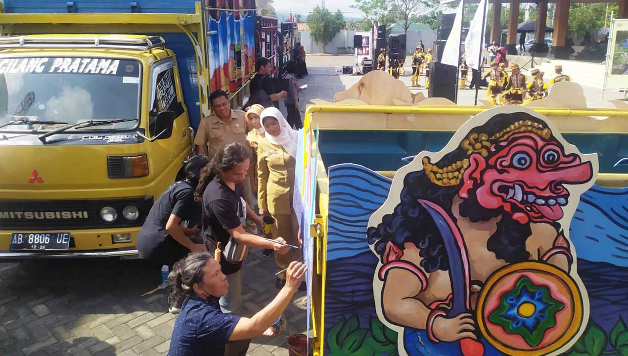 KESEIMBANGAN: Kepala Dinas Kebudayaan (Kundha Kabudayan) Kulonprogo Niken Probo Laras menyaksikan langsung perupa Kulonprogo melukis truk latar gelaran puncak penutupan FKY di TBK, Pengasih, Kulonprogo, kemarin (19/9).(HENDRI UTOMO/RADAR JOGJA)