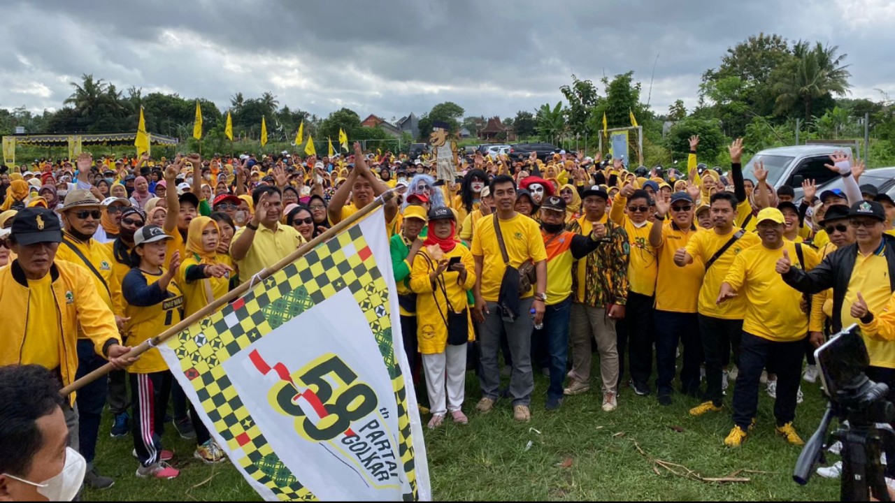 NYAWIJI: Ketua DPD Partai Golkar Sleman Janu Ismadi mengibarkan bendera start jalan sehat di Lapangan Warak, Sumberadi, Mlati, Minggu (16/10/2022). (YOGI IP/RADAR JOGJA)