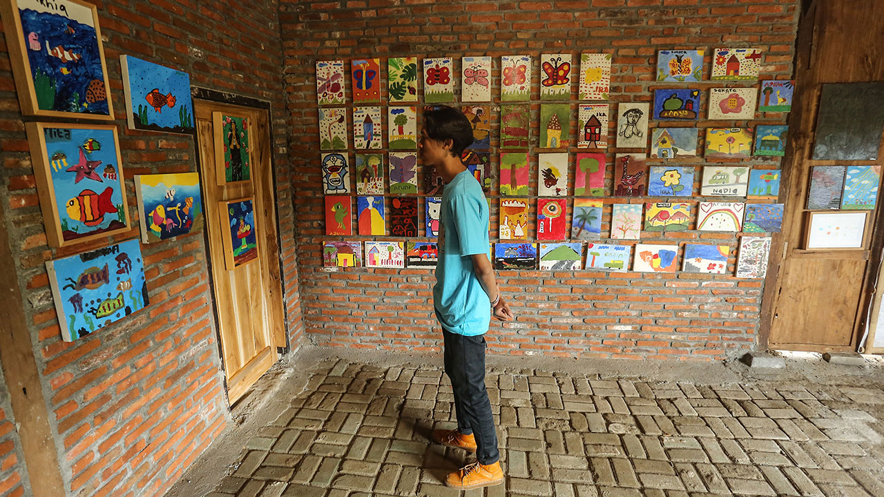 KREATIF: Petugas mengamati lukisan karya anak-anak di Sekolah Sungai Siluk, Selopamioro, Imogiri kemarin (30/10). Sebanyak 720 gambar dipamerkan dalam Pameran Sewu Lukisan #4 mulai 29 Oktober-5 November.(ELANG KHARISMA DEWANGGA/RADAR JOGJA )