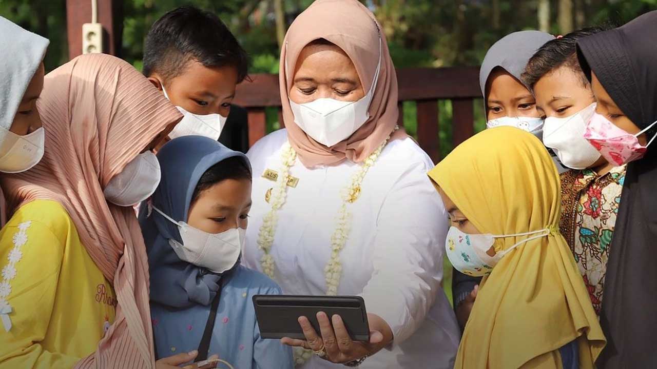 PANUTAN: Bupati Sleman Kustini Sri Purnomo menunjukkan laman edukasi melalui ponselnya di hadapan anak-anak dengan memanfaatkan fasilitas internet wifi gratis.(ISTIMEWA)