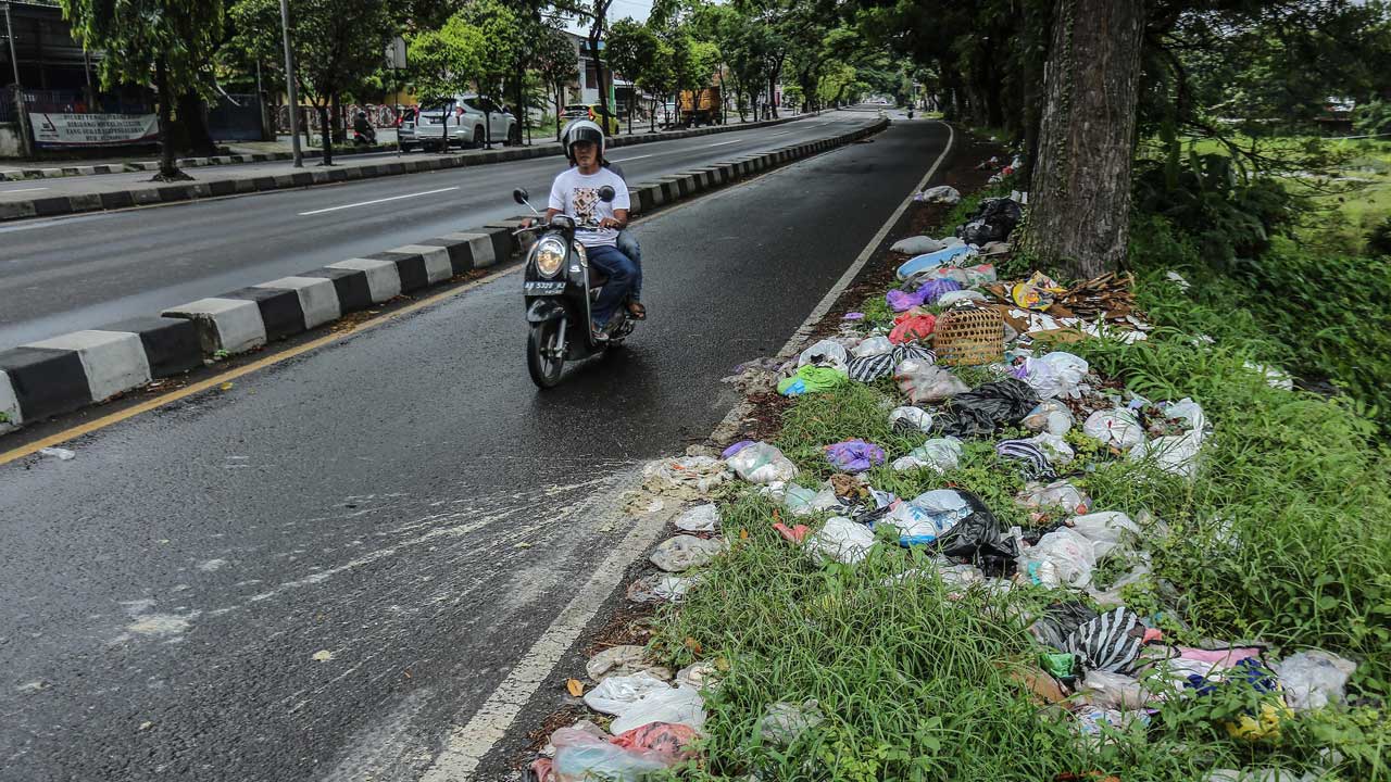 BERSERAKAN : Pengendara motor melintas di samping tumpukan sampah liar di Ring Road Timur, Banguntapan, Bantul, kemarin (1/11). Perlunya penindakan dilakukan untuk membuat jera pembuang sampah sembarangan.(ELANG KHARISMA DEWANGGA/RADAR JOGJA)