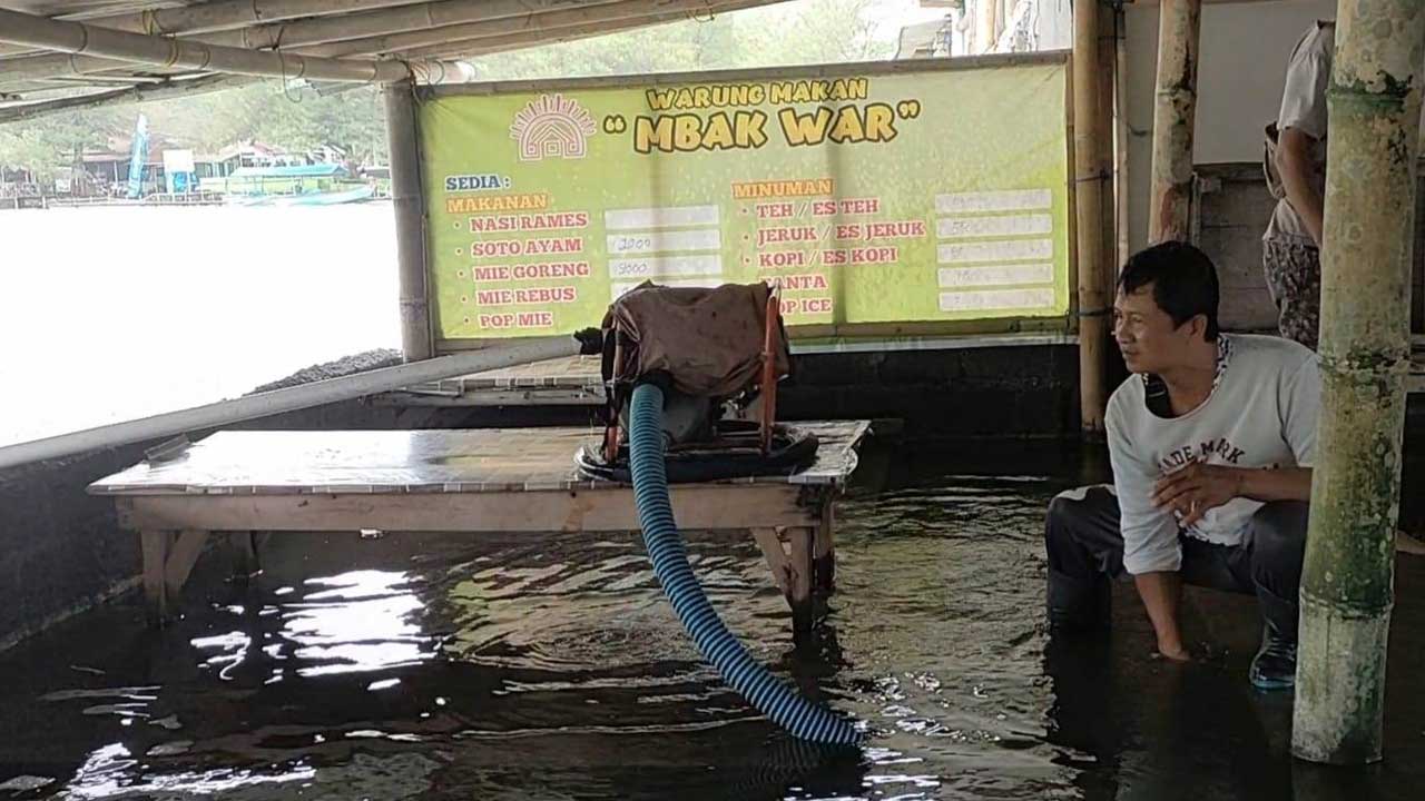 LIBUR BANJIR: Salah satu pedagang kuliner di dekat laguna Glagah mencoba menguras genangan banjir menggunakan mesin pompa, kemarin.(HENDRI UTOMO)