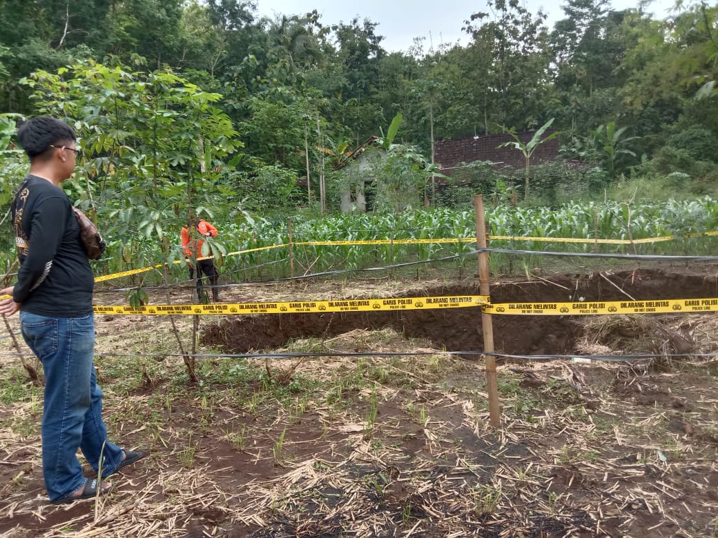 MENGANGA - Petugas memasang police line di lokasi tanah amblas lahan pertanian wilayah Padukuhan Sumberan, RT 1/9, Kalurahan Kenteng, Kapanewon Ponjong, Minggu (26/2). (Dokumentasi Dukuh Sumberan Ika Apriyani)