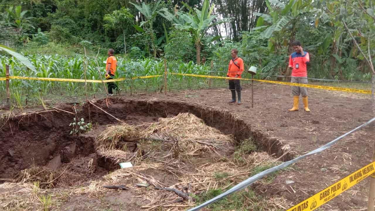 MEMBAHAYAKAN - Petugas memasang police line di lokasi tanah amblas lahan pertanian wilayah Padukuhan Sumberan, RT 1/9, Kalurahan Kenteng, Kapanewon Ponjong, Minggu (26/2).(Foto Dukuh Sumberan, Ika Apriyani untuk Radar Jogja)