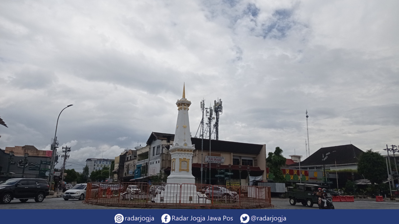 MENDUNG : Warga melintasi kawasan Simpang Empat Tugu Pal Putih Jogjakarta, Selasa (14/3). (DWI AGUS/RADAR JOGJA)