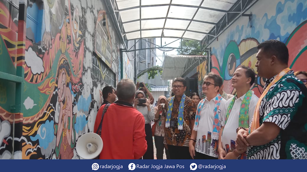 WISATA : Salah satu warga Suryatmajan tengah memberikan penjelasan terkait stori di balik gambar mural, Kamis (16/3). (ANNISSA KARIN/RADAR JOGJA)