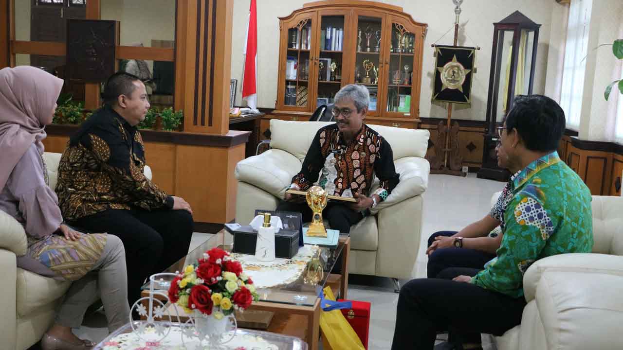 DISERAHKAN: Staf Ahli Bupati Bidang Kesra dan SDM Bambang Sutrisno menyerahkan UHC Award kepada Pj Bupati Kulonprogo Tri Saktiyana di ruang kerja bupati setempat, kemarin (24/3).(DOK HUMAS KP)
