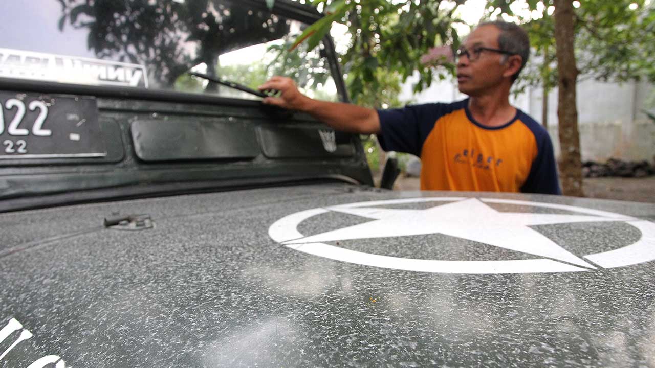 TERDAMPAK: Suharyanto menunjukkan abu vulkanik Gunung Merapi yang menempel pada mobilnya, di Dusun Kaliurang Barat, Hargobinangun (15/3). Hujan abu tipis dampak erupsi Merapi dilaporkan melanda wilayah Kaliurang dan Turi.(GUNTUR AGA TIRTANA/RADAR JOGJA)