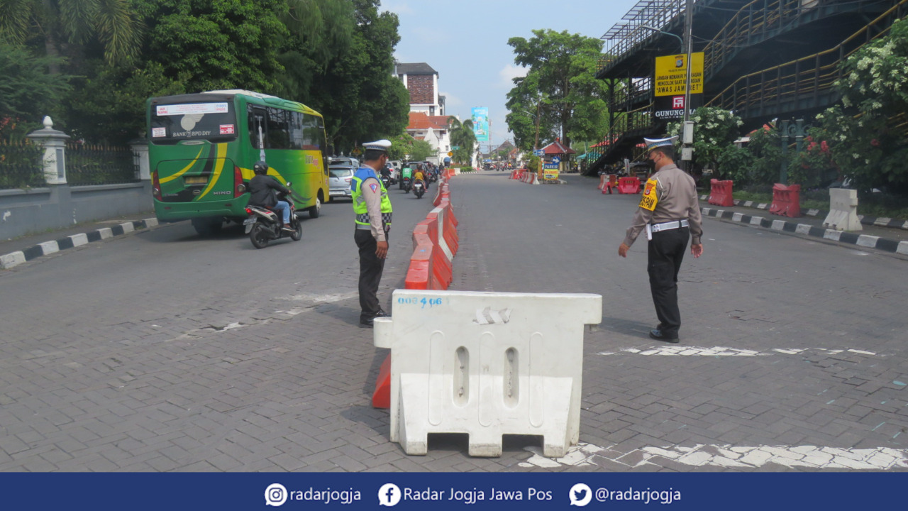 MENATA : Personil Satlantas Polresta Jogja tengah menata water barrier di Jalan Abu Bakar Ali, Selasa (18/4). (DWI AGUS/RADAR JOGJA)