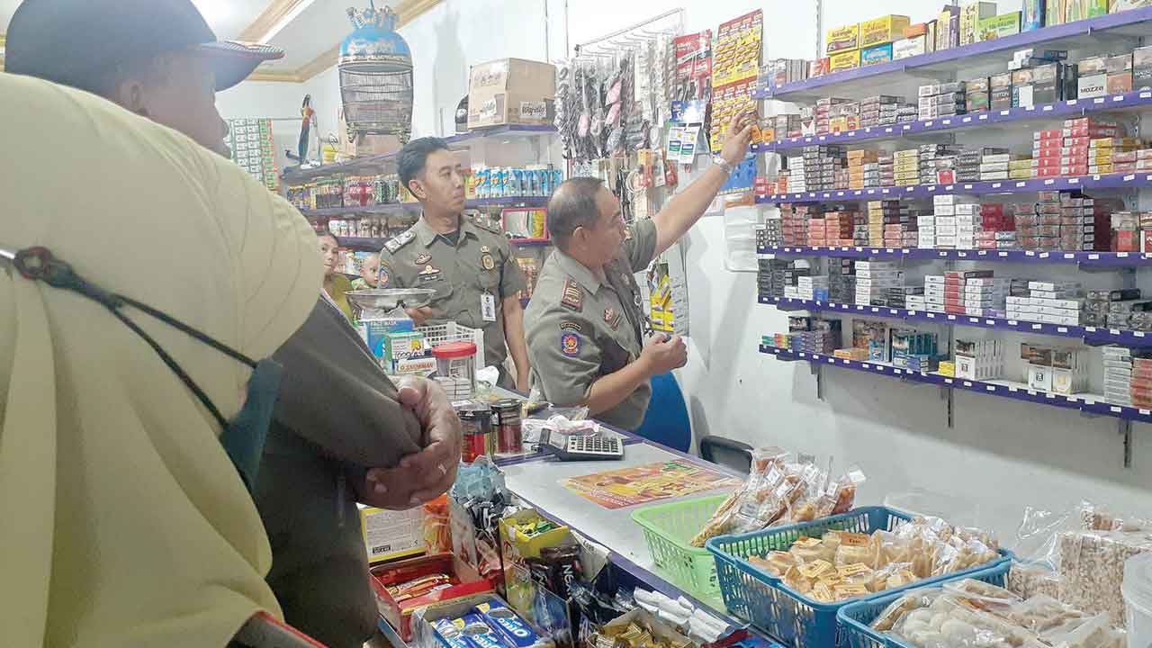 PENCEGAHAN: Anggota Satpol PP Kota Jogja melakukan operasi dan sosialisasi pencegahan peredaran rokok ilegal ke warung-warung. RIZKY WAHYU/RADAR JOGJA