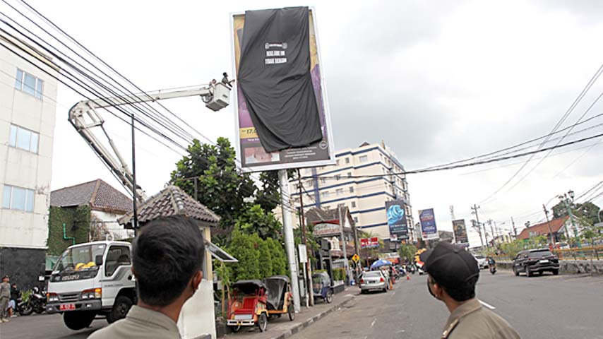 DITUTUP: Petugas Satpol PP Kota Jogja melakukan penertiban berupa penutupan dua reklame yang tidak berizin di Jalan Pasar Kembang, Kota Jogja, kemarin (9/5). (Foto: Guntur Aga Tirtana/Radar Jogja)