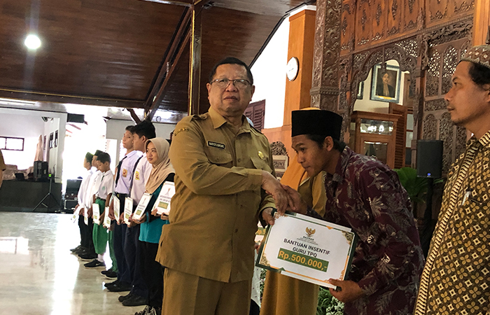 SALING MEMBERI: Bupati Tulungagagung Maryoto Birowo menyalurkan bantuan insentif guru TPQ kepada salah satu guru TPQ yang mewakili.