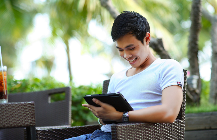 BAHAGIA : Seorang pria sedang menatap layar gadgetnya sambil tersenyum