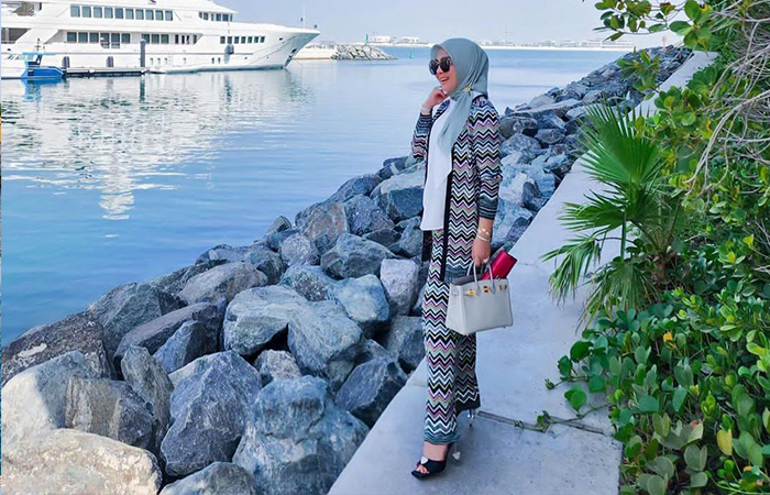 Syahrini berdiri tegak di dekat batu yang estetik.