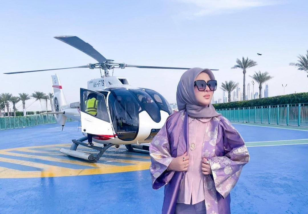 Syahrini berpose di depan helikopter.