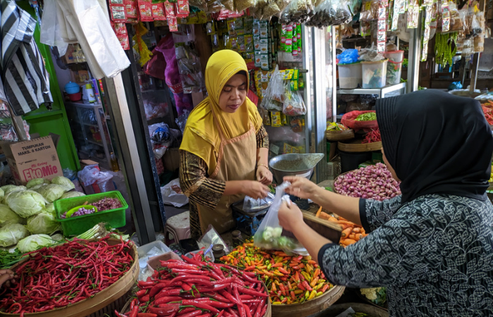 Salah satu penjual kebutuhan pokok di Pasar Basah Trenggalek sedang melayani seorang pembeli.