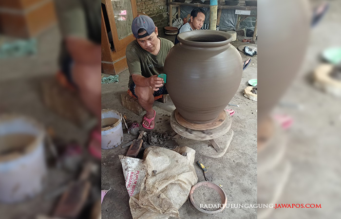 TEKUN: Mukhtaromin sedang membuat gerabah berbentuk guci.
