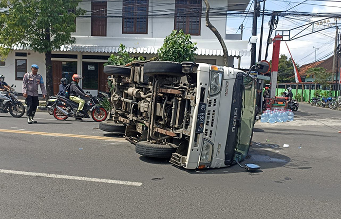 GLINCIR: Truk boks isi ratusan galon air mineral terguling di Jalan  Pahlawan Kedungwaru pada Sabtu (15/7) lalu.