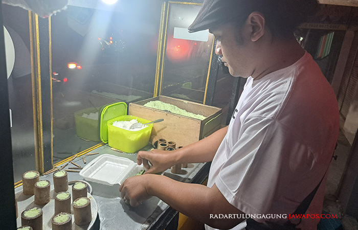 MASIH DIMINATI: Azis menyiapkan 1 porsi pesanan kue puthu untuk pembelinya kemarin. Saat ini jajanan lawas tersebut cukup sulit ditemukan.