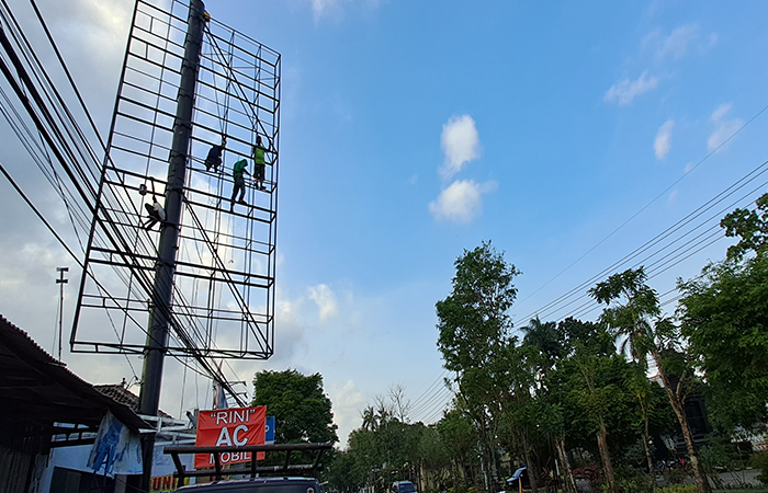 BESAR:  Pekerja saat memasang reklame di Jalan Pahlawan, Kecamatan Kedungwaru.