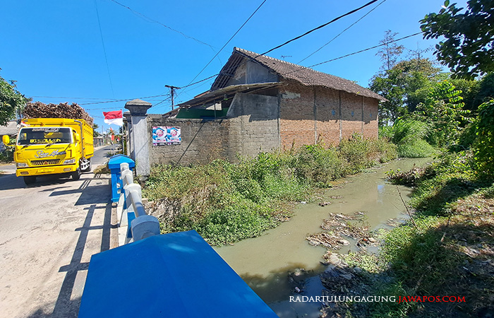 MENYENGAT HIDUNG: Pengendara melintas di jembatan Sungai Tempur di Desa Purworejo Kecamatan Sanankulon. Tidak hanya keruh, sungai ini juga mengeluarkan bau tak sedap.