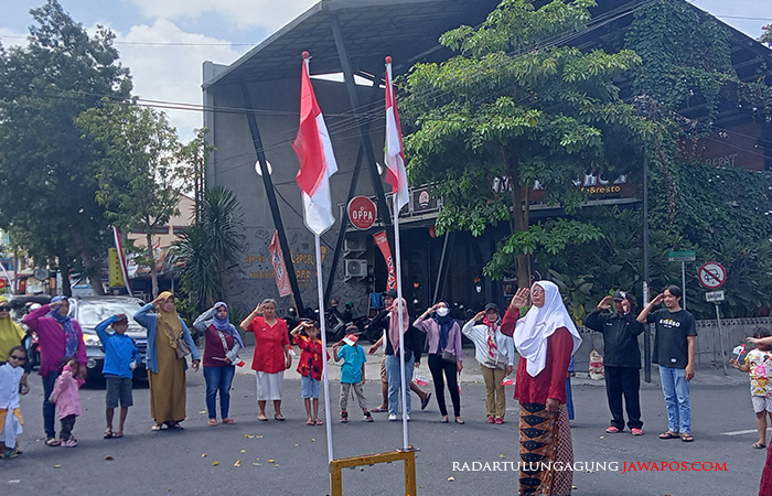 NASIONALISME: Warga dan pengendara berhenti sejenak di perempatan untuk menghormasi bendera merah putih, kemarin (17/8).