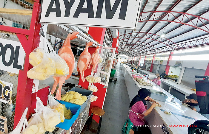 REPLIKA: Sri, salah seorang penjual ayam potong di Pasar Templek, memasang replika ayam palsu untuk menggaet pembeli, Sabtu (19/8).