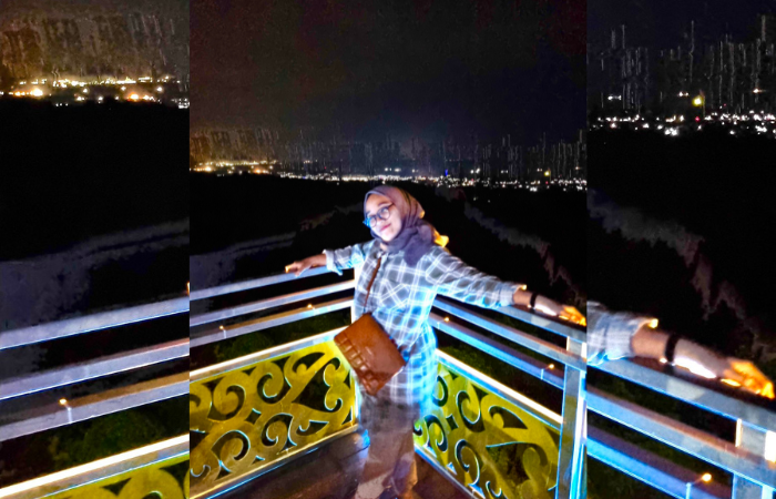 Terlihat seorang wanita sedang berfoto dengan latar belakang gemerlap kota, diisukan sebagai Kota Modern, Saranjana