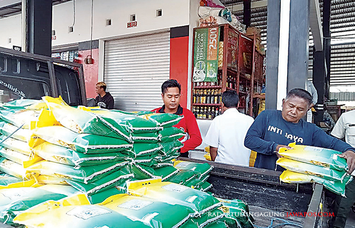 SEMANGAT : Pedagang di Pasar Pon memikul beras hasil distribusi Disperindag Kota Blitar dan Bulog, kemarin (29/8).