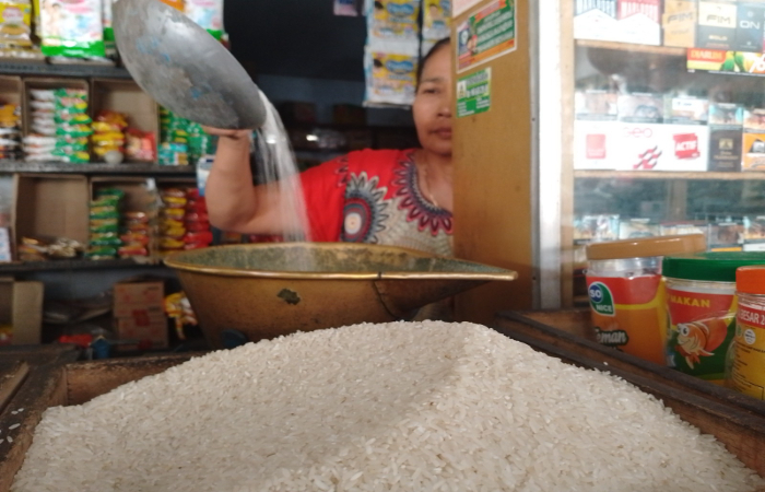 BELUM NORMAL: Seorang pedagang sembako di Pasar Nglegok menimbang beras di lapaknya.