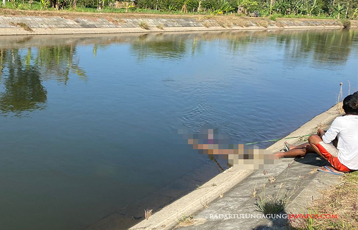 HANYUT: Seorang warga sedang mengevakuasi jasad yang hanyut di Sungai Lodagong.