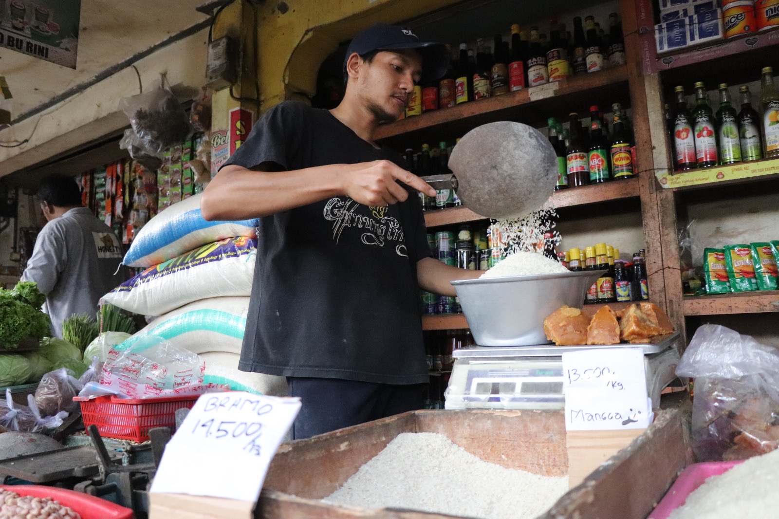 MEMBUMBUNG: Pedagang beras Pasar Ngemplak, Tulungagung sedang menimbang barang dagangannya.