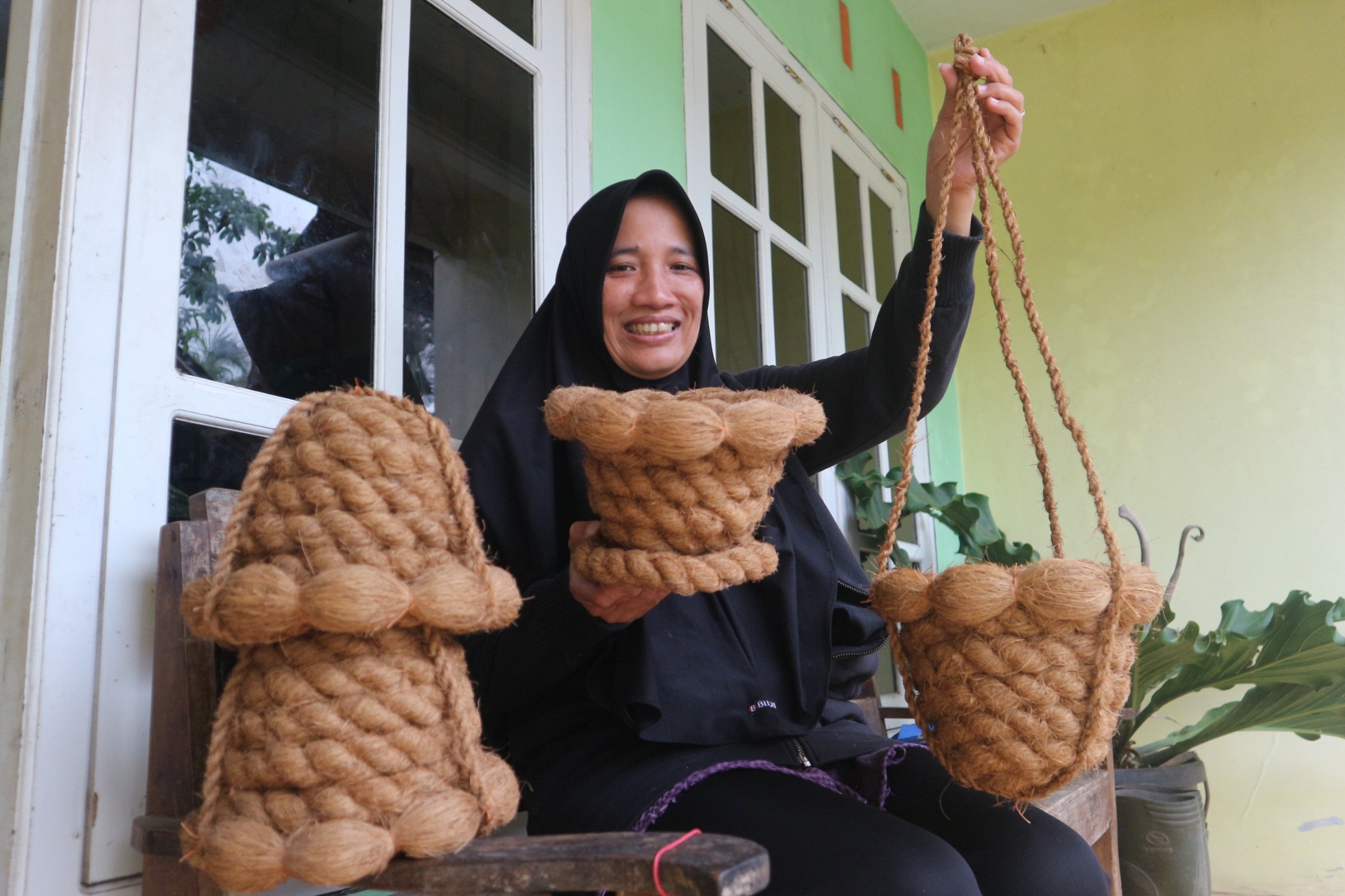 TERUS PRODUKSI: Sri Astutik, ibu rumah tangga sekaligus mantan TKI, menunjukkan pot berbahan dasar sabut kelapa bikinannya, kemarin (11/10).