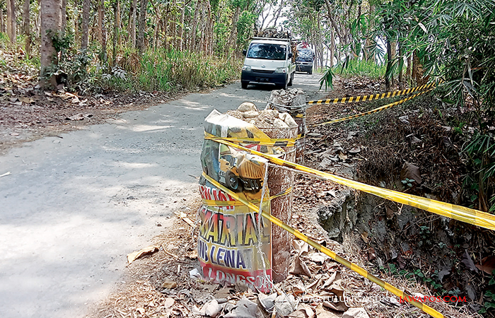 GARA-GARA LONGSOR: Pengendara beroda empat harus melewati secara bergiliran karena setengah jembatan telah longsor.